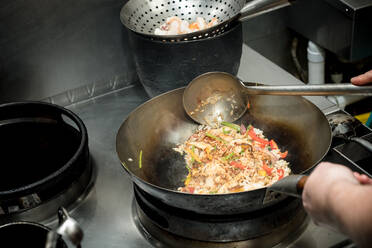 Hohe Winkel der Ernte anonymen Koch braten Reis mit Gemüse im Wok beim Kochen Gericht mit Garnelen in der Küche des Restaurants - ADSF29539