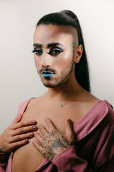 Portrait of glamorous transgender bearded woman in sophisticated make looking at camera against neutral background - ADSF29558