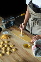 Unrecognizable person preparing raviolis and pasta at home. She is painting the pasta with eggs - ADSF29568