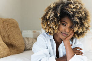 Attraktive afroamerikanische Frau, die sich auf dem Bett ausruht und in die Kamera schaut - ADSF29609