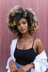 Confident African American female wearing stylish casual outfit looking at camera standing against colorful door - ADSF29615