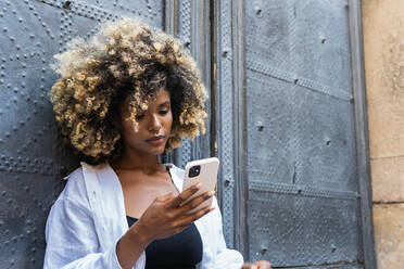 Serene attractive African American female in casual outfit sitting talking on cellphone while smiling widely - ADSF29616