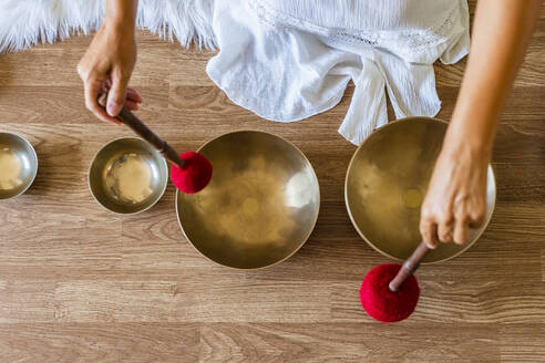 Therapist playing brass singing bowl with mallet on floor - DLTSF02135