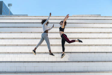 Frauen strecken die Hände beim Springen auf der Treppe - AFVF09129