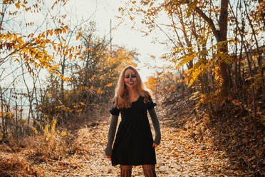 Lächelnde Frau mit Halloween-Make-up steht im Wald im Herbst - MRRF01461