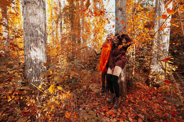 Happy friends with Halloween costume and make-up standing in forest during autumn - MRRF01468
