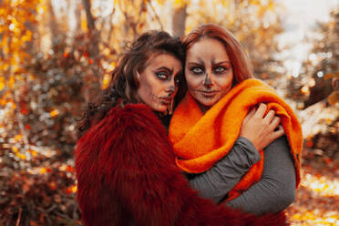 Frau mit Halloween-Make-up umarmt Freundin im Wald - MRRF01473