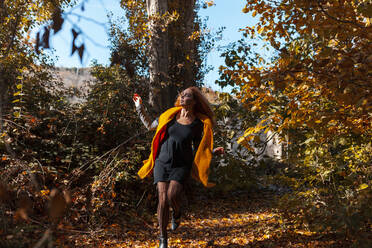 Woman with spooky make-up running in forest during Halloween - MRRF01477