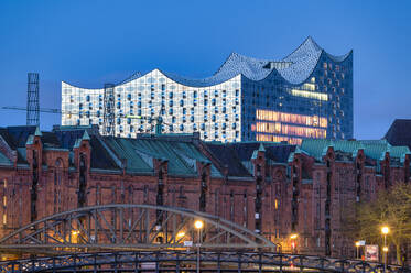 Deutschland, Hamburg, Lagerhäuser der historischen Speicherstadt in der Morgendämmerung mit Elbphilharmonie im Hintergrund - RJF00880