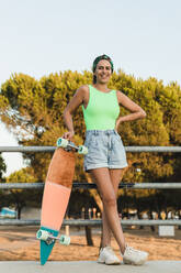 Lächelnde Frau mit Hand auf der Hüfte im Skateboardpark - JRVF01767