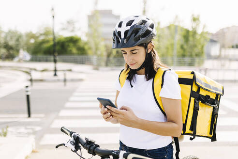 Zustellerin benutzt Mobiltelefon, während sie auf der Straße steht - XLGF02240