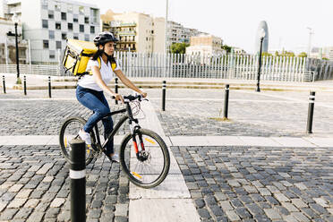 Weibliche Zustellerin fährt Fahrrad auf der Straße in der Stadt - XLGF02245