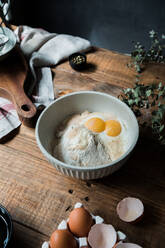 From above bowl with eggs and cream mixed with bread crumbs and flour on wooden table during pastry preparation - ADSF29847