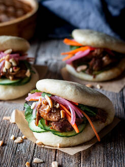Harmful lush wheat bao buns with fresh vegetables and juicy meat on wooden table - ADSF29913