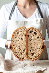 Crop gesichtslose Frau Hände halten frisch gebackenen Sauerteig Roggenbrot Krume weiß Schneiden in der Hälfte - ADSF29915