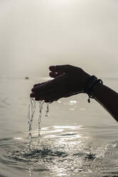 Crop faceless female with handful of water in wet hands in sea in morning in Alcudia - ADSF29947