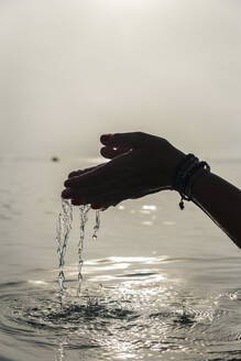 Crop gesichtslose Frau mit einer Handvoll Wasser in nassen Händen im Meer am Morgen in Alcudia - ADSF29947