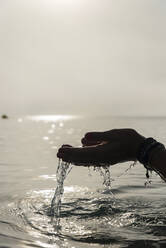 Crop gesichtslose Frau mit einer Handvoll Wasser in nassen Händen im Meer am Morgen in Alcudia - ADSF29948