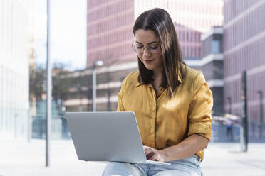 Businesswoman working on laptop while sitting at office park - PNAF02155