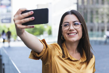 Smiling female professional taking selfie through mobile phone at office park - PNAF02159