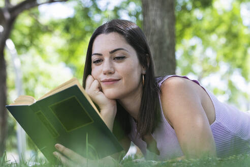 Beautiful woman reading book in public park - PNAF02163