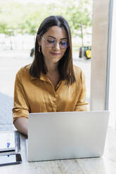 Geschäftsfrau arbeitet an einem Laptop in einem Café - PNAF02177