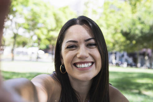 Lächelnde schöne Frau nimmt Selfie im öffentlichen Park - PNAF02188
