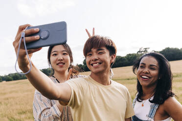 Lächelnde Freunde nehmen Selfie durch Handy im Park - ASGF01390