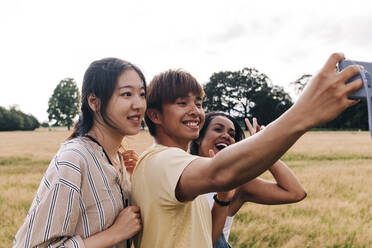 Glückliche Freunde nehmen Selfie durch Smartphone im Park - ASGF01391