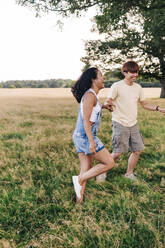 Cheerful friends holding hands while enjoying at park - ASGF01411