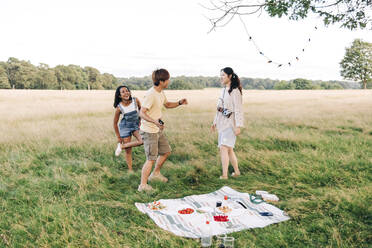 Glückliche Freunde tanzen beim Picknick auf der Wiese - ASGF01416