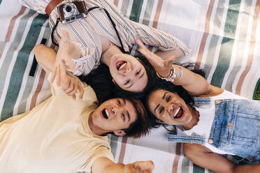 Friends screaming while relaxing on picnic blanket - ASGF01420