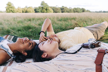 Smiling friends resting together during picnic at park - ASGF01421