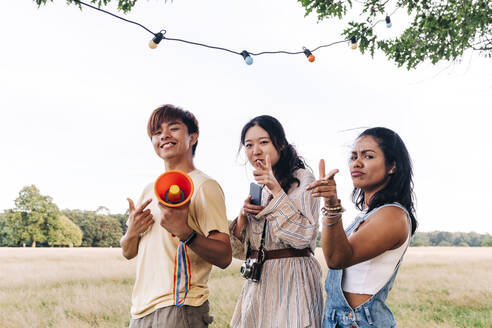 Friends pointing while standing on meadow - ASGF01432