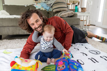 Man and baby boy playing with toys in the living room. - CAVF94722