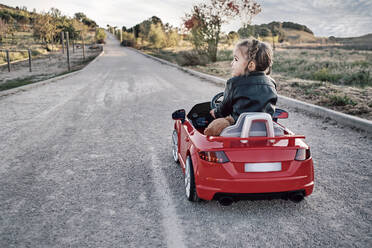 Ein Mädchen fährt ein Spielzeugauto - CAVF94754