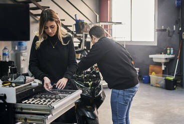 Eine Frau und ein Mann arbeiten zusammen in einer Autowerkstatt - CAVF94783