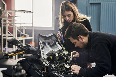 Eine Frau und ein Mann arbeiten zusammen in einer Autowerkstatt - CAVF94784