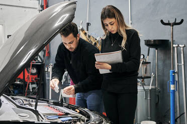 Zwei Mechaniker helfen sich gegenseitig bei der Arbeit in einer Werkstatt - CAVF94786