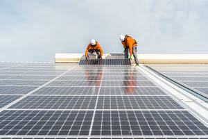 Unrecognizable solar panel technicians teamworking in Spanish factory - CAVF94816