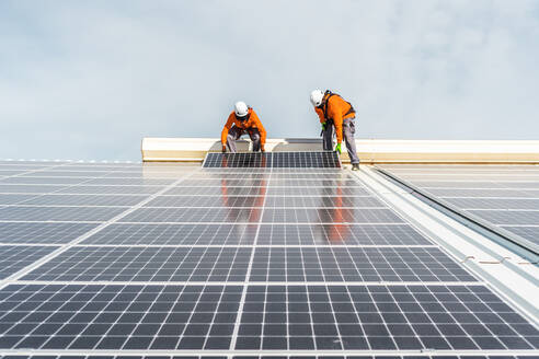 Unrecognizable solar panel technicians teamworking in Spanish factory - CAVF94816