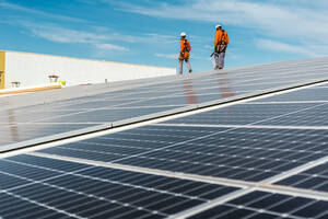 Installation mit mehreren Solarmodulen mit Technikern auf dem Rücken - CAVF94820