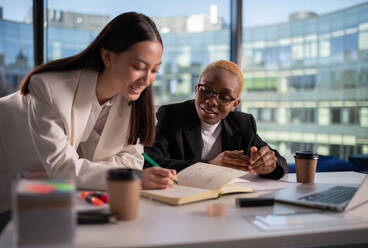 Positive diverse businesswoman making notes in office - CAVF94835