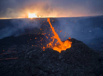 Brennend heiße Lava spritzt im Vulkankrater bei bedecktem Abend - CAVF94841