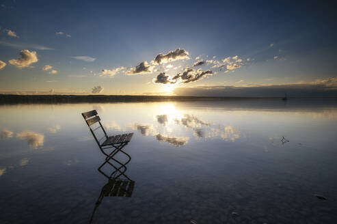 Leerer Stuhl im Wasser stehend bei stimmungsvollem Sonnenuntergang - MBOF00042