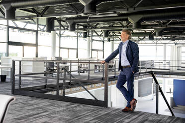 Businessman with hand in pocket standing by railing in office - PESF03177