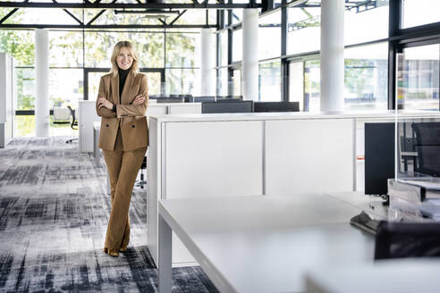 Confident female professional with arms crossed standing in office - PESF03189