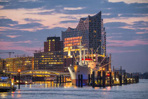 Deutschland, Hamburg, Schiff angedockt in der HafenCity in der Morgendämmerung mit Elbphilharmonie im Hintergrund - RJF00891