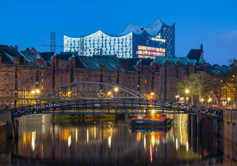 Deutschland, Hamburg, Brücke über den Kanal in der historischen Speicherstadt in der Morgendämmerung mit Elbphilharmonie im Hintergrund - RJF00892