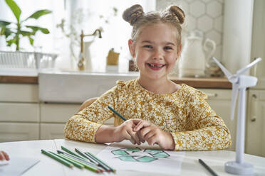 Lächelndes Mädchen mit Haarknoten sitzt am Tisch - ABIF01572